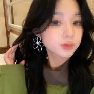 Detailed view of model wearing large 3D line flower earrings in a silver finish