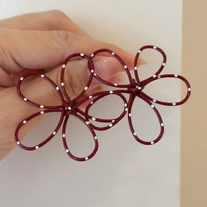 Detailed view of dark red wire-frame flower earrings with white polka dots for woman