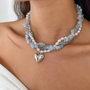 Gedetailleerd overzicht van gelaagde ketting met parels, blauwe stenen en zilveren hartje