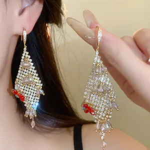 Detailed view of rhinestone-encrusted flower tassel earrings on model.
