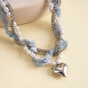 Detail van een gelaagde parelketting met blauwe stenen en een hartjes hanger