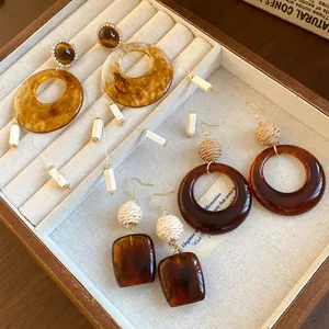 Nahaufnahme von vintage braunen Acryl- und Stroh-Ohrringen in einem Displayfach