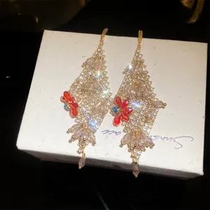 Close-up of sparkling zircon flower tassel drop earrings shown on a white textured jewelry gift box