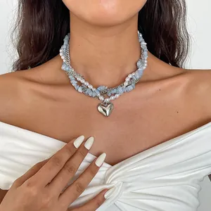 Detailweergave van een gelaagde ketting met parels, blauwe stenen en een hartvormige hanger.