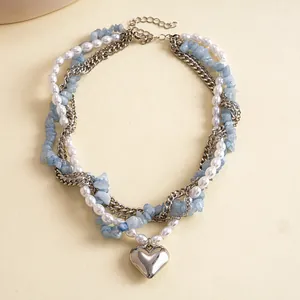 Detailopname van vintage meerlaagse ketting met parels, blauwe stenen en zilveren hart.