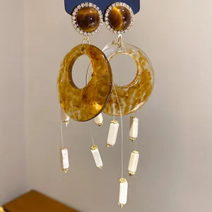 Makro-Nahaufnahme von Vintage-Acryl-Ohrringen in Braun mit hängenden weißen Marmorperlen