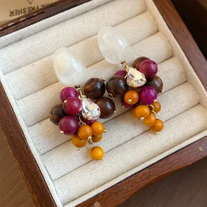 Detail van boho oorbellen van hars en hout met kristallen in een crèmekleurig sieradendoosje