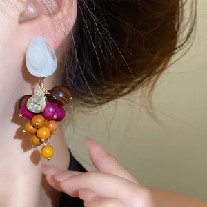 Gedetailleerde close-up van boho oorbellen met houten kralen, hars stud en kristal