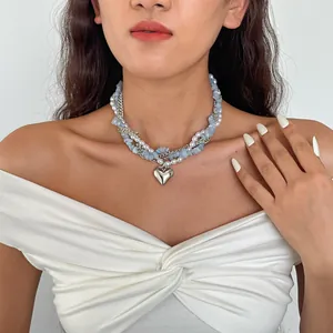 Gedetailleerd beeld van een gelaagde ketting met parels en blauwe stenen op model