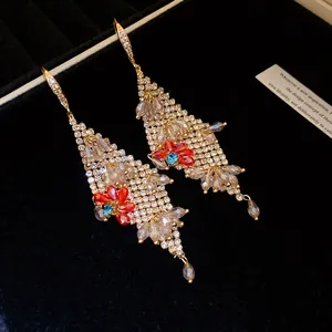 Close-up of luxury gold-tone earrings featuring sparkling zircon flowers and crystal tassels.