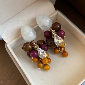 Detailweergave van handgemaakte houten kralen en hars kwastjes oorbellen met kristal.