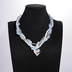 Gedetailleerd beeld van een meerlaagse ketting met parels, blauwe stenen en hartje.