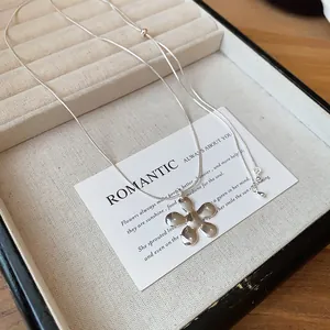 Detail view of a silver flower pendant necklace on a minimalist snake chain