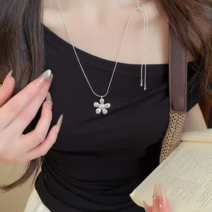 Minimalist silver flower pendant necklace worn by a model in a lifestyle setting.