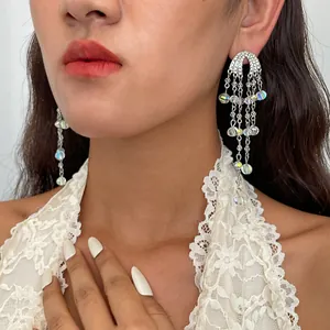 Close-up van model met stijlvolle strass glazen kralen kwastje oorbellen en wit kanten topje.
