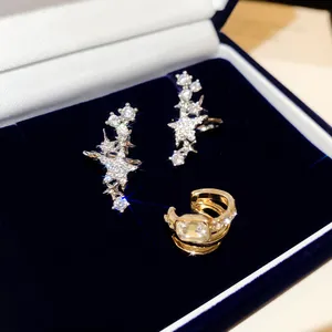 Detailaufnahme funkelnder Stern-Zirkonia-Ohrringe und goldener Ohrmanschette in Box.