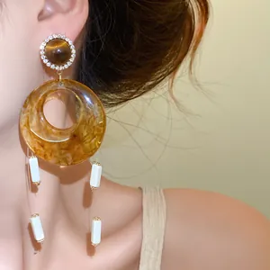Nahaufnahme von Vintage-Bernstein-Acryl-Ohrringen mit eleganten weißen Anhängern