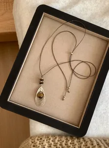 Gedetailleerde weergave van vintage tijgeroog hanger met gouden draad in display