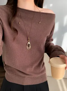 Detailweergave van een retro-halsketting met tijgeroog-hanger bij een bruine trui