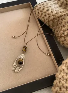 Detail van een retro halsketting met tijgeroogsteen hanger en bruin lederen koord