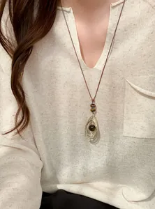 Detail van een retro leren koord ketting met tijgeroog hanger gedragen door een model.