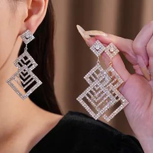 Orecchini geometrici traforati con diamanti, mostrati sull'orecchio e sulla mano.