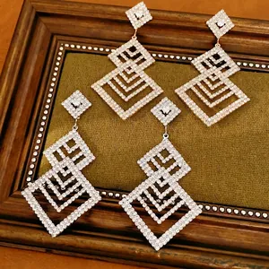 Eleganti orecchini geometrici traforati in oro e argento con diamanti brillanti in cornice.