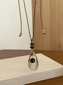 Detailopname van retro tijgeroogsteen hanger ketting met metalen traanvorm