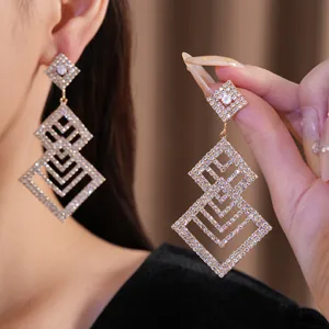 Nahaufnahme von luxuriösen, mehrlagigen Strass-Ohrringen in Rautenform mit Gold-Finish