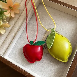 Handcrafted leather fruit pendants with apple and lemon designs on colored cords