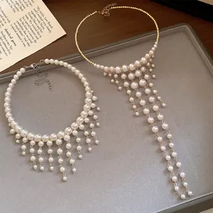 Detail of French palace style pearl chokers with elegant tassel design on gray tray.