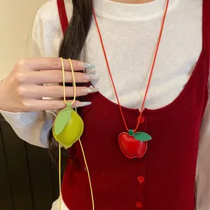 Detailaufnahme von süßen Leder-Halsketten mit Apfel- und Zitronenanhängern auf Weste