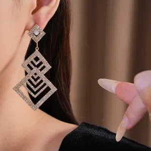 Detailansicht der eleganten geometrischen Strass-Ohrhänger in Goldoptik direkt am Ohr