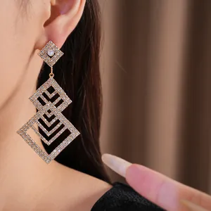 Detailansicht von luxuriösen mit Strass besetzten Rauten-Ohrhängern am Ohr des Models