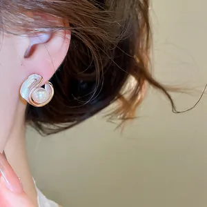 Close-up of elegant French style pearl earring with white enamel swirl design