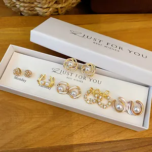 Detailed view of a set of six pearl and rhinestone earrings in a white gift box