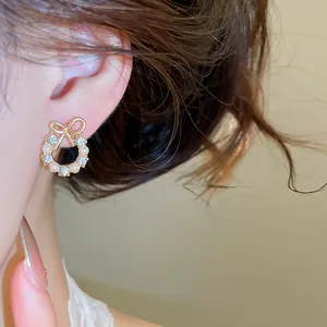 Close-up of elegant bow-knot wreath earrings with pearls and rhinestones