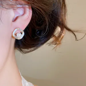 Detail shot of French style enamel pearl earrings with sparkling diamond accents.