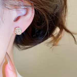 Macro detail of elegant French-style pearl and rhinestone stud earring on ear