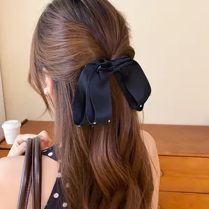 Detail van zwarte stoffen strik haarklem met strass steentjes op golvend haar.