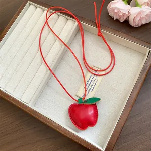 Rote Leder-Apfel-Anhänger-Halskette in einer hochwertigen hölzernen Schmuckbox.