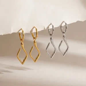 Detailansicht von minimalistischen unregelmäßigen Wellen-Ohrringen in Gold und Silber.