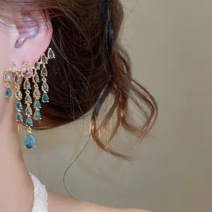 Gros plan détaillé de boucles d'oreilles élégantes en zircon bleu et transparent sur l'oreille