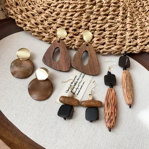 Détail de boucles d'oreilles en bois de style ethnique rétro sur toile de lin naturel.