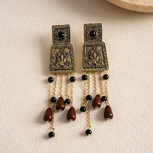 Detail shot of vintage distressed gold earrings with acrylic teardrop tassels.