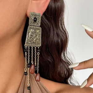 Detail view of vintage gold tassel earrings with acrylic beads worn by a model ears