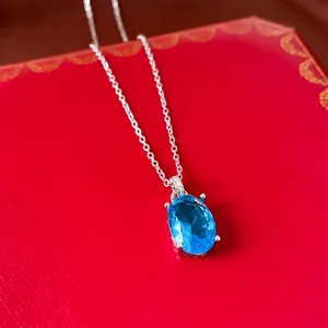 Elegante Silberhalskette mit ovalem blauem Zirkon-Anhänger auf rotem Luxusbox-Hintergrund.