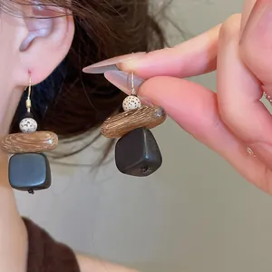 Gros plan sur des boucles d'oreilles pendantes géométriques en bois au style ethnique