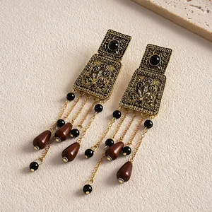Detail showing vintage bronze metal texture and brown acrylic teardrop tassels