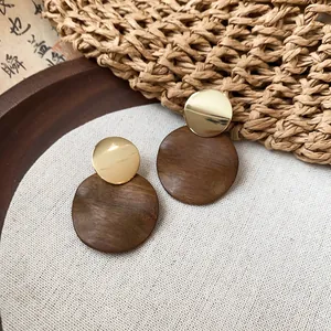 Gros plan détaillé de boucles d'oreilles rondes en bois et métal doré sur toile de lin